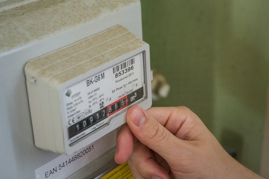 Hand an einem Energiemessgerät, das den Stromverbrauch misst